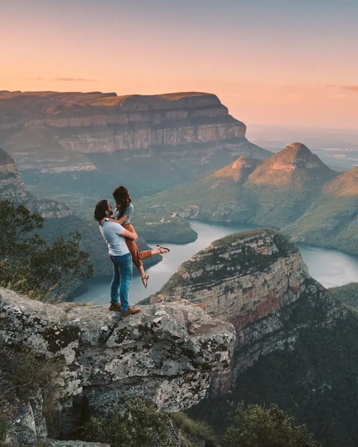 A couple in love embracing atop a scenic South African canyon during sunset.